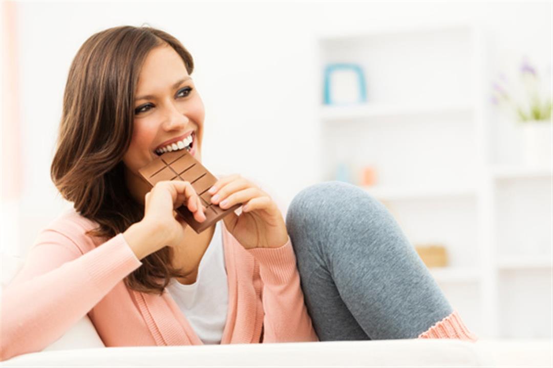 happy-woman-taking-bite-of-chocolate-bar_y4f5qu