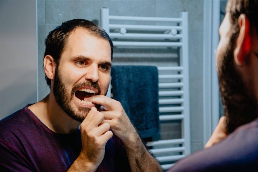 man-flossing-teeth-mirror