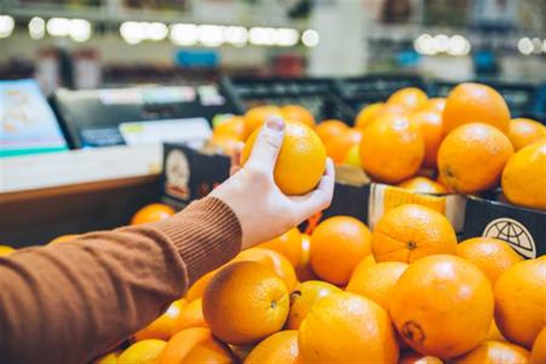 96913148-man-choose-oranges-from-shelf-of-store-shopping-concept