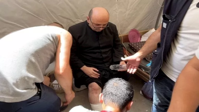 الأب جبرائيل رومانيلي، يتلقى العناية الطبية بعد إصابته بجروح في ساقه إثر غارة إسرائيلية على الكنيسة