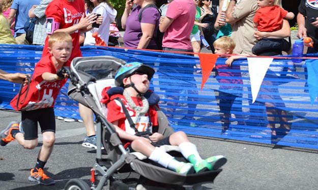 بالصور- طفل يشارك أخيه من ''ذوي الاحتياجات الخاصة'' في سباق ثلاثي