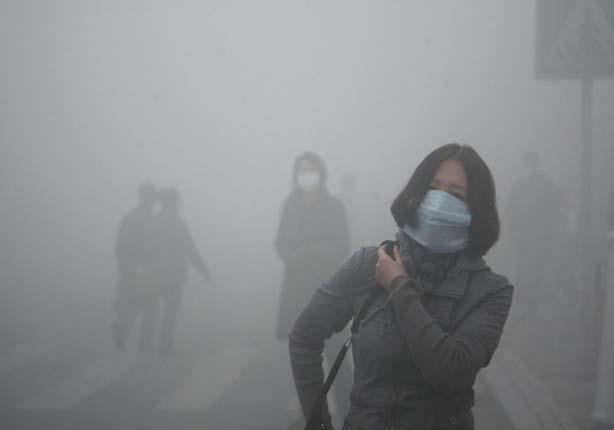 فتاة تسير خلال الضباب الدخاني في بكين مرتدية قناعا عازلا، حيث تزيد جسيمات التلوث الصغيرة 40 مرة عن المعيار الدولي للسلامة.                            