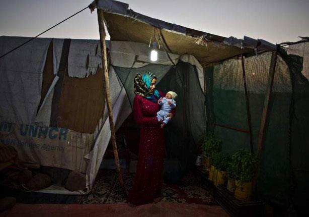 سوريات بمخيمات اللاجئين يحملن أطفالهن الرضع                                                                                                                                                             