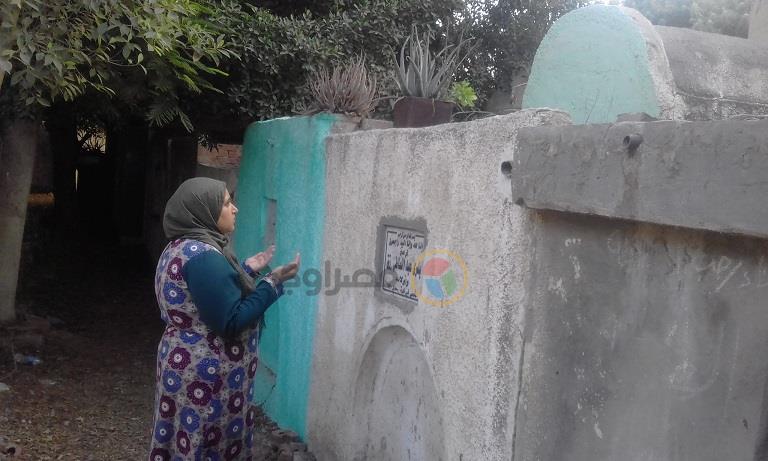 الأم غادة تقرأ الفاتحة على قبر طفلين من أبنائها                                                                                                                                                         