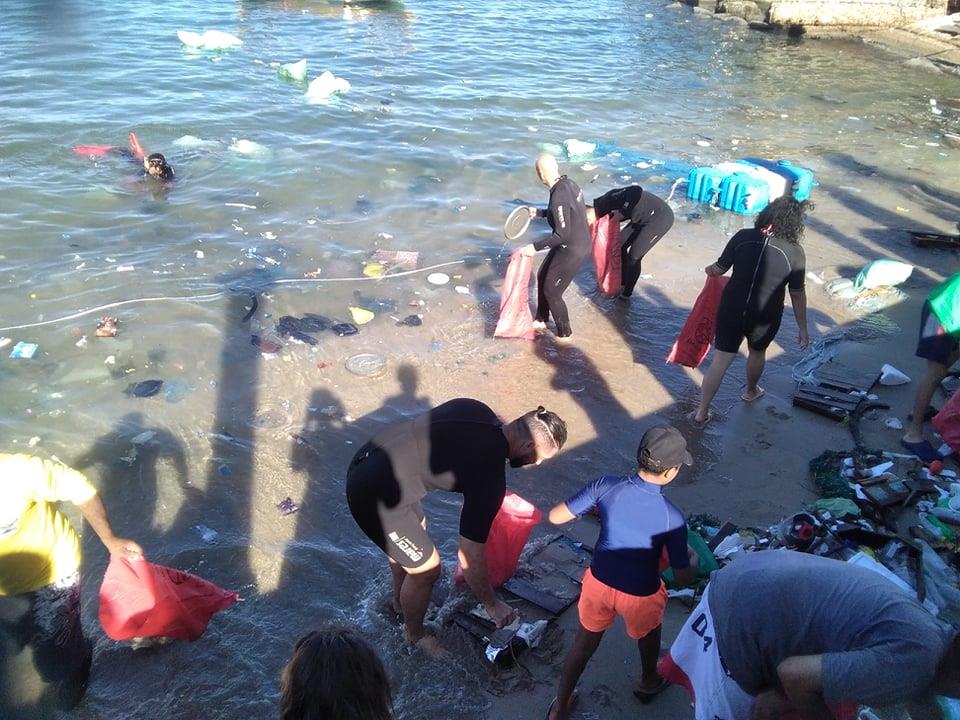 أجانب ومصريون يجمعون المخلفات من مياه ساحل الإسكندرية 