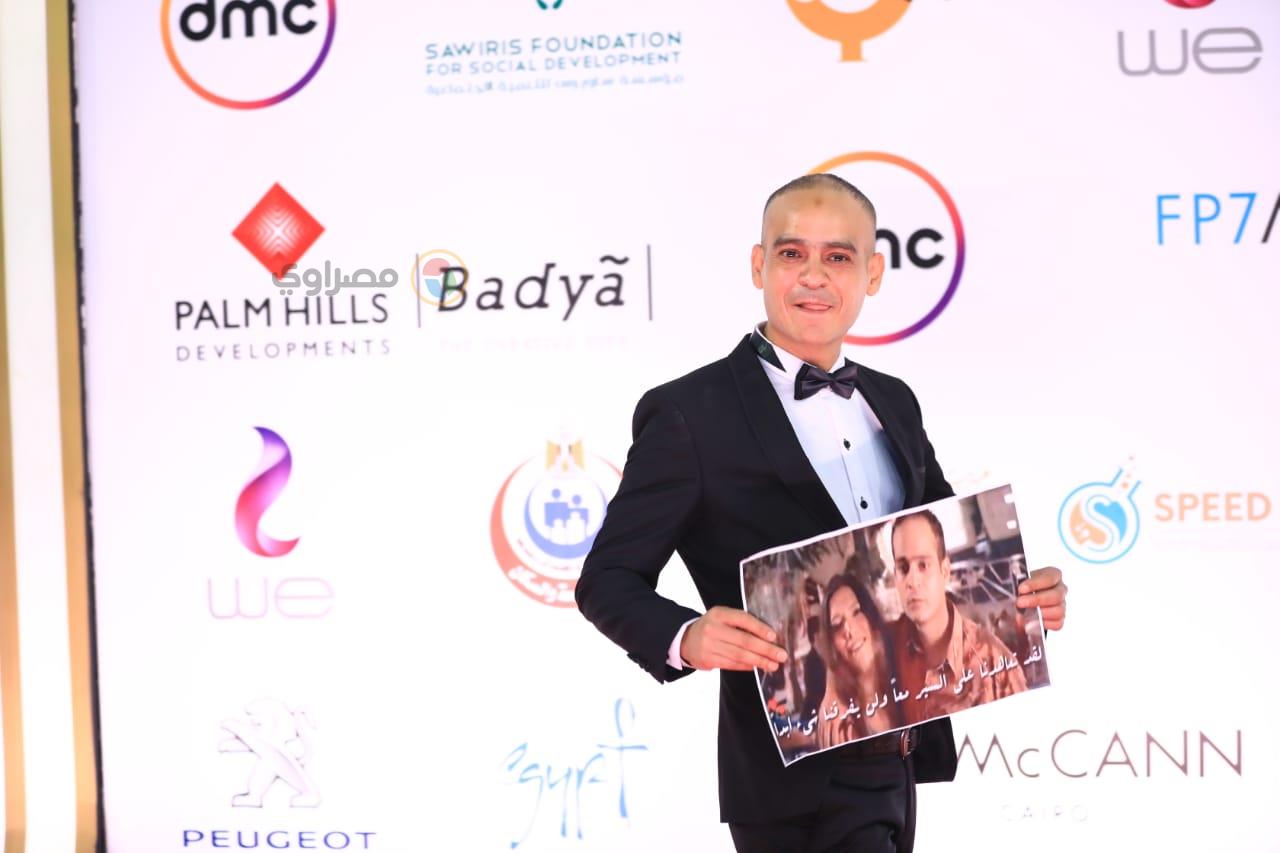 مصطفى عباس يحمل صورة من أحد أعماله بمهرجان القاهرة السينمائي 