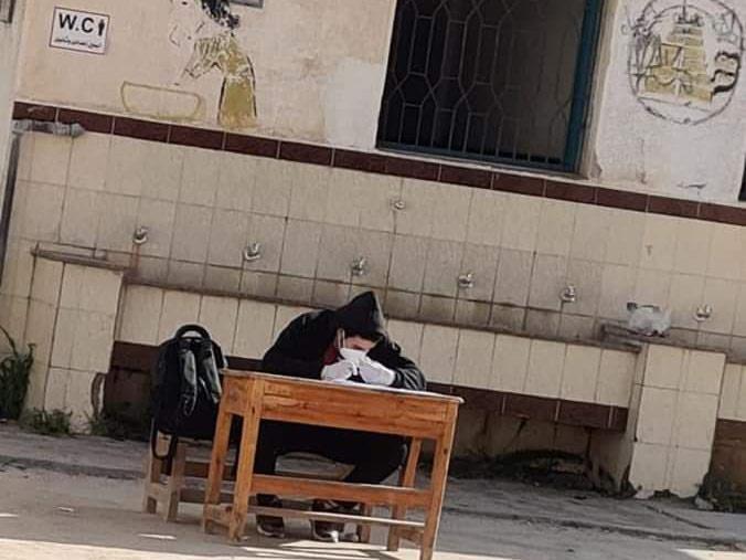 الطالب أثناء أداءه الامتحان في فناء المدرسة
