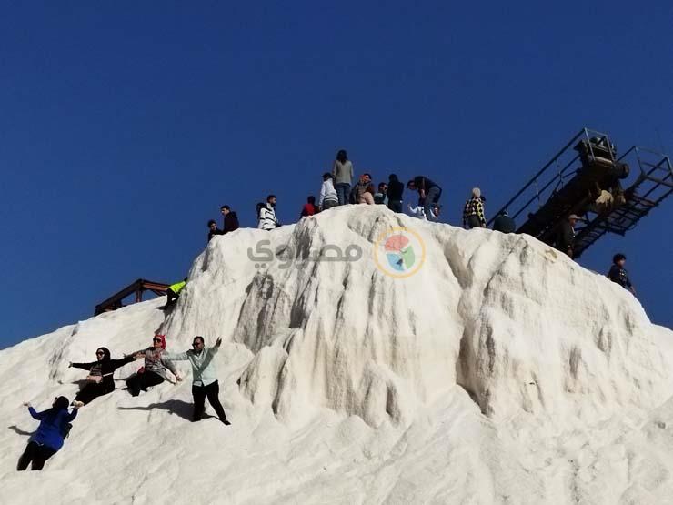 مواطنون يستمتعون بالشمس المشرقة على جبال الملح في بورسعيد
