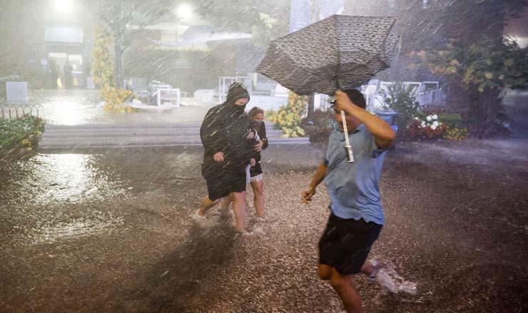 أشخاص يصارعون الأمطار الغزيرة في ممرات غمرتها الفيضانات بمركز بيلي جين كينج الوطني للتنس الذي ضرته بقايا إعصار إيدا فلاشينغ ميدوز  بنيويورك