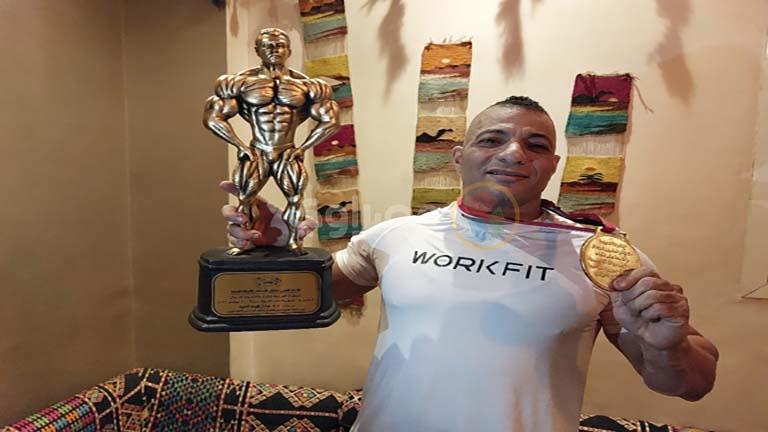 البطل محمود عنبر رافعًا تمثال لاعب كمال الأجسام