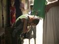 رجل يسكب الماء على رأس فتى في قطاع غزة بسبب الحر ف