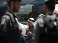 شرطي من خفر الحدود الاسرائليلي يدقق في هوية فلسطين