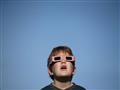 A-boy-uses-solar-viewing-glasses-as-the-sun-emerges-through-fog-cover-before-the-solar-eclipse-in-De                                                                                                    