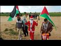 فلسطيني يوزع ورود على حدود غزة بملابس سانتا كلوز (4)                                                                                                                                                    