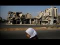 امرأة تسير أمام مبان مدمرة في حمص (أرشيف)