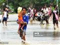 أحد المواطنين يحمل طفله عبر مياه الفيضانات                                                                                                                                                              