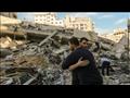 فلسطينيان يتعانقان أمام أنقاض مبنى دمر في غارة اسر