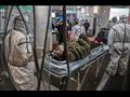 عاملون طبيون يرتدون ملابس واقية برفقة مريض في مستشفى الصليب الأحمر في ووهان