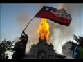 متظاهر يلوح بعلم تشيلي أمام كنيسة الصعود التي تحتر