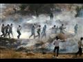  متظاهرون فلسطينيون يركضون وسط دخان الغاز المسيل ل