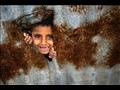 طفل فلسطيني ينظر من فتحة في لوح زينك مستخدم كجدار 