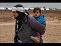 امرأة سورية تحمل على ظهرها طفلا في مخيم واشوكاني ل