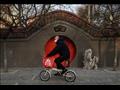 رجل يقود دراجته في بكين مُرتديا كمامة