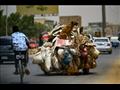 فتى سوداني يعبر على دراجته قرب مركبة تنقل القمامة 