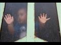 طفل عراقي ينظر إلى الخارج من خلال زجاج نافذة في ظل