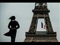 امرأة ترتدي قناعاً واقياً أمام برج إيفل في باريس