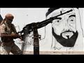 مقاتل يمني يقف بجانب جدارية لمؤسس دولة الإمارات ال