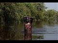 رجل يحمل كيسًا من الحبوب لعائلته على أرض مرتفعة ويقطع 10 كيلومترات (6.2 ميلًا) في مياه الفيضانات