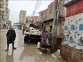 عمال النظافة يرفعون القمامة من شوارع الفيوم تحت الأمطار (3)