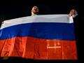  متظاهران يحملان العلم الروسي خلال الاحتجاج على قر