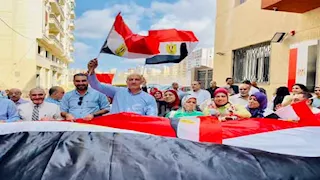 طلاب ومعلمو الإسكندرية يرفعون أطول علم لدعم المشاركة في الانتخابات -صور