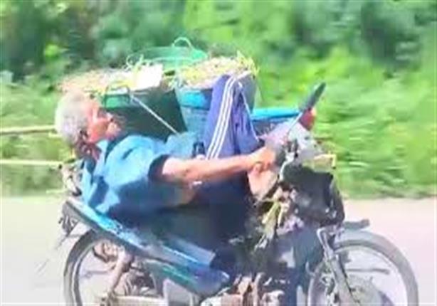عجوز يقود دراجة نارية بيد واحدة وهو مستلقٍ على ظهره‏
