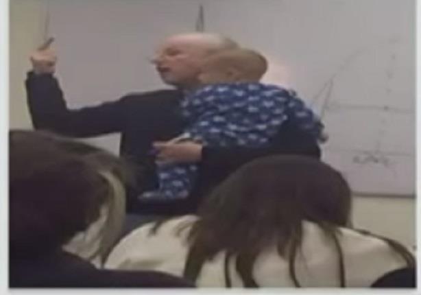 صورة تٌظهر "إنسانية معلم" ليحمل طفل إبن أحد طالبات الفصل الدراسى