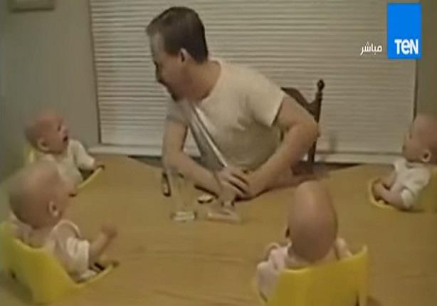 اربع اطفال يضحكون بطريقة هيستيرية امام والدهم على طاولة