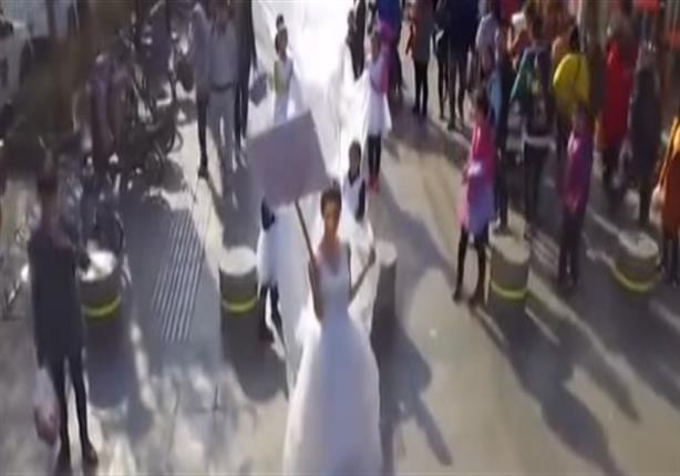 سيدة تسير في الشارع بفستان زفاف "طوله 100 متر"