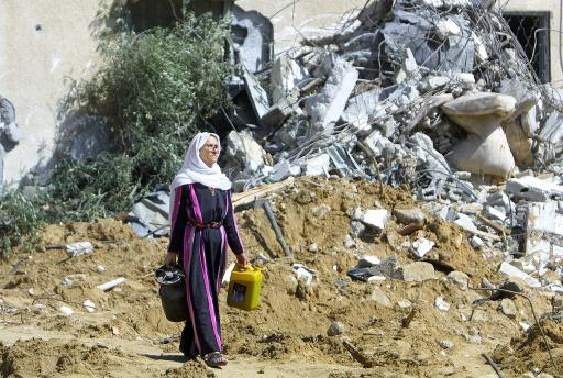 سيدة فلسطينية تمر امام كومة من الركام حيث كان منزل