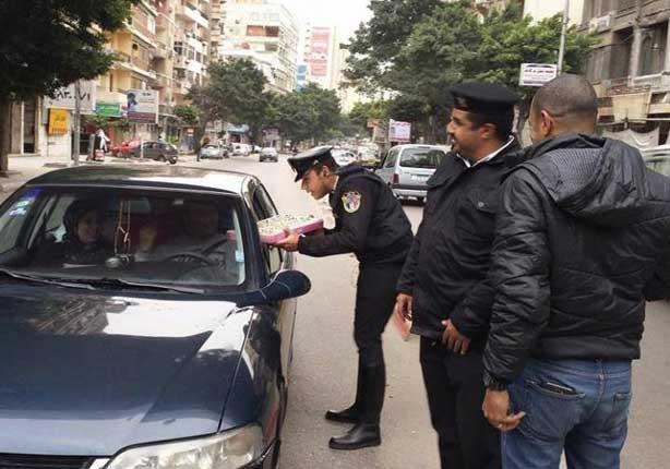 ضباط شرطة يقدمون الحلوى لمواطنين في ذكرى الثورة