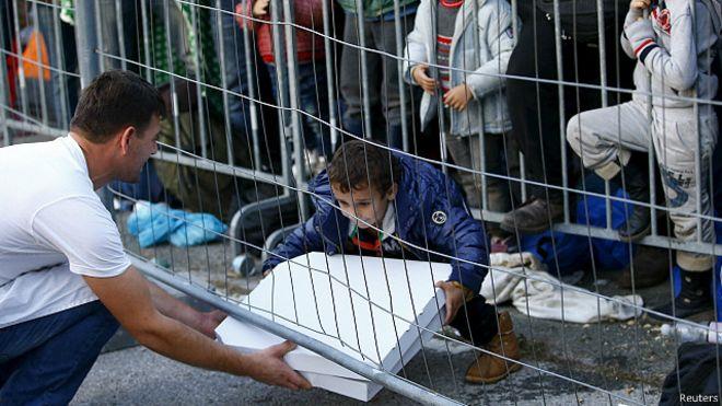 شخص يقدم طعاما لطفل لاجئ عند الحدود السلوفينية الن