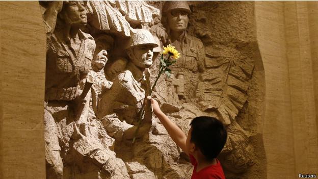 طفل صيني يضع الزهور على نصب في متحف "حرب المقاومة"