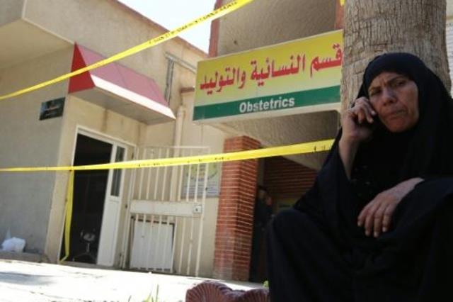 امرأة عراقية تجلس امام المستشفى حيث حدث الحريق