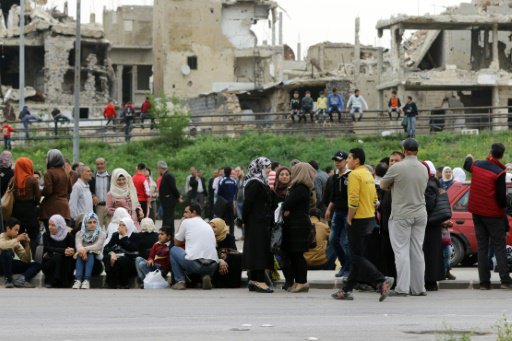 نازحون سوريون ينتظرون قدوم حافلة لنقلهم من حمص (وس