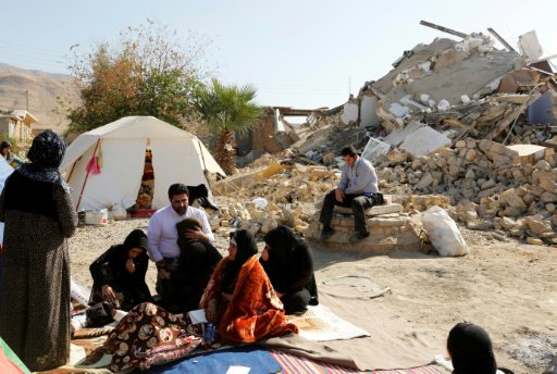 ايرانيون يجلسون أمام منازلهم المدمرة في بلدة كويك 