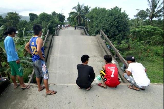 فيليبينيون يتفقدون جسرا تضرر جراء الزلزال في سوريغ