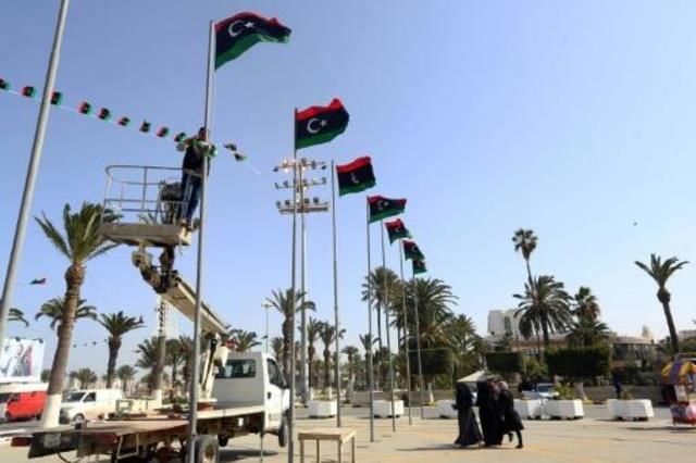 عمال يعلقون الاعلام الليبية في ساحة الشهداء بطرابل