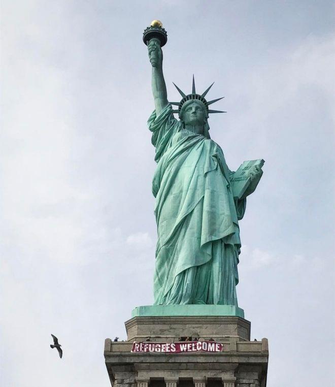 تعليق شعار مرحبا باللاجئين على تمثال الحرية
