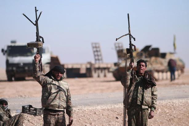 جنود بقوات سوريا الديمقراطية يرفعون أسلحتهم أثناء 